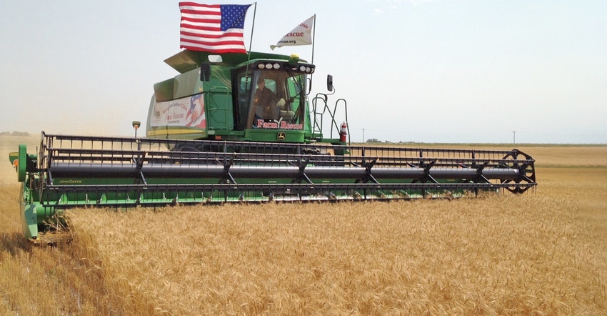 Farm Rescue combine flies the American flag as it harvests wheat