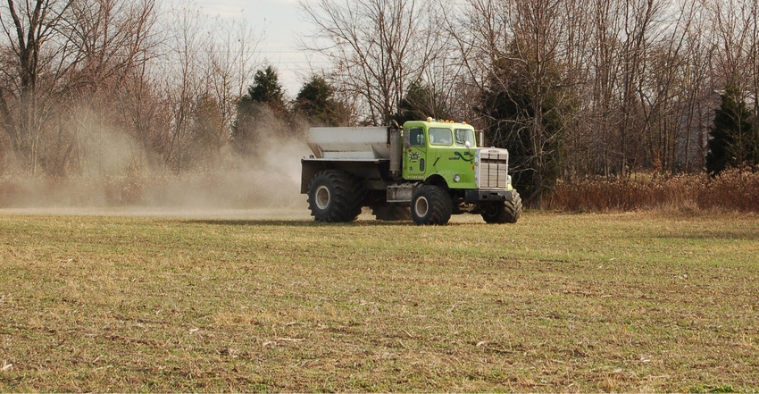 truck spreading fertilizer in farm field