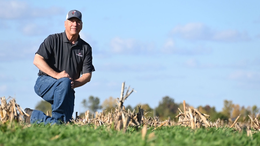Chris Hausman kneeling in a field of cover crops