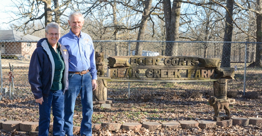 Connie and Freman Elam standing in front of Boer Goats Bear Creek Farm sign