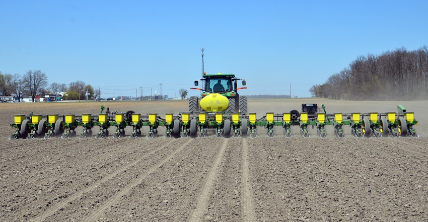 John Deere tractor and planter driving across field John Deere tractor and planter driving across field