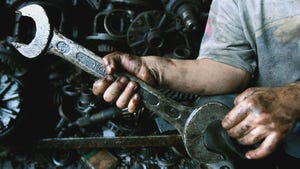 Child holds a wrench in a greasy factory.