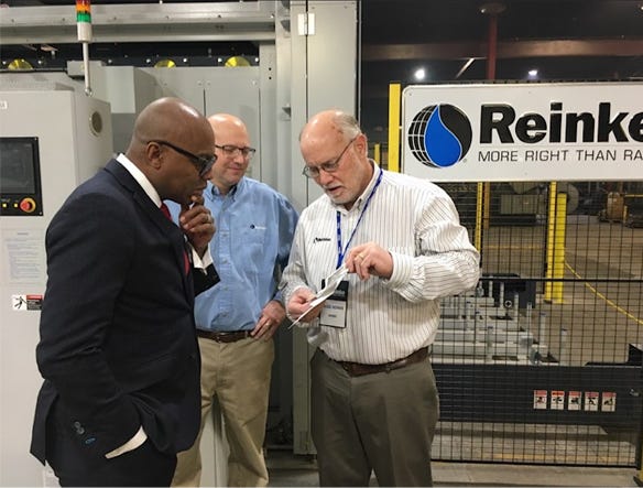 Russ Reinke shows Anthony Goins, director of Nebraska Department of Economic Development, old photos of the first Reinke pivot 