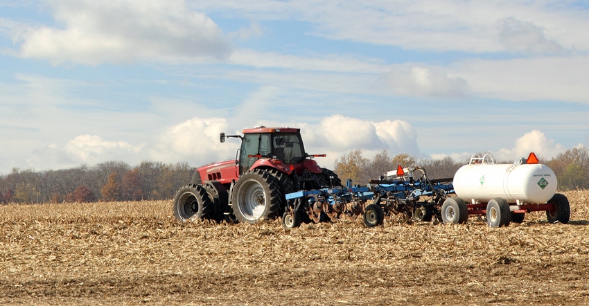 Tractor applying anhydrous ammonia to field with corn stubble