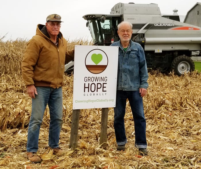 Jim Schmidt and Bill Hare in harvested cornfield with Growing Hope Globally sign