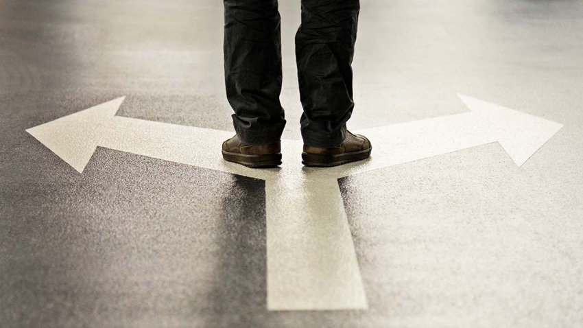 Person standing where two arrows split representing decision Person standing where two arrows split representing decision