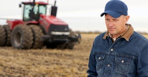 Farmer in field with combine looking stressed