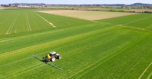 aerial view of tractor spraying fertilizer on field
