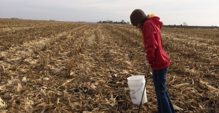 girl in dead corn field taking soil samples