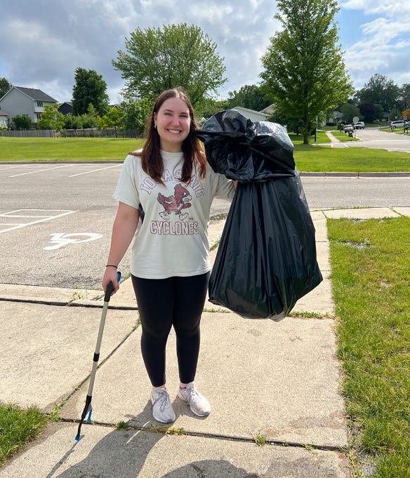 Intern Sarah Brackett holding garbage bag cleaning up at College Creek