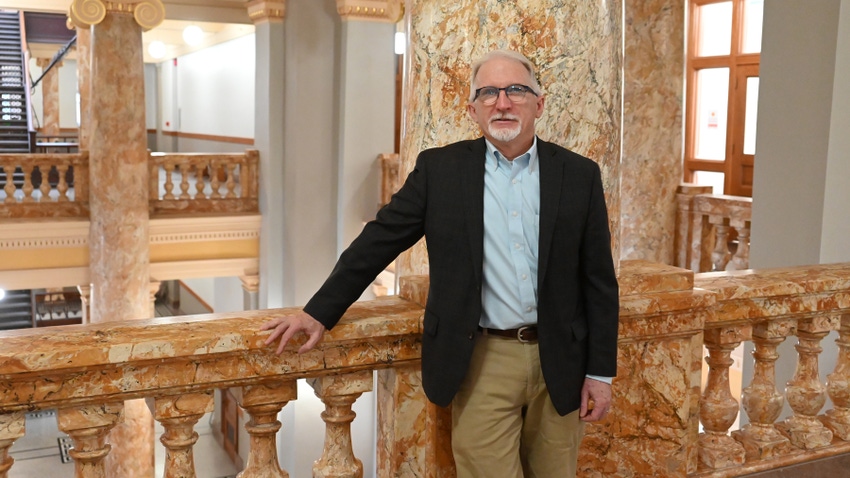 John Lawrence standing next to marble railing in building John Lawrence standing next to marble railing in building