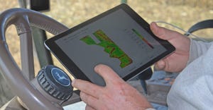 farmer holding tablet in tractor cab