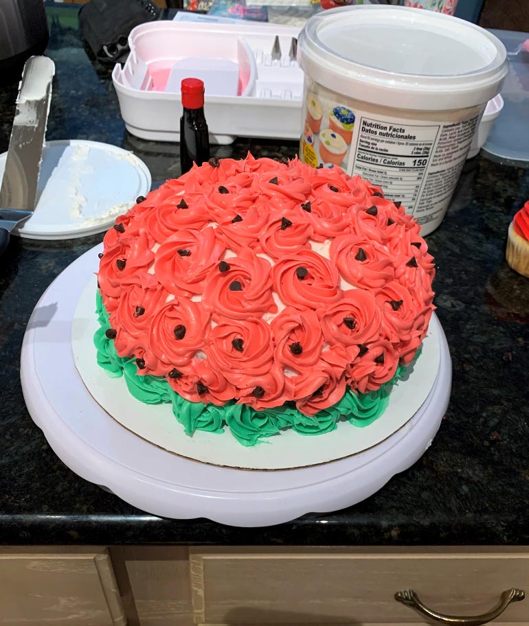 A small cake on a counter top, decorated with green and red frosting 