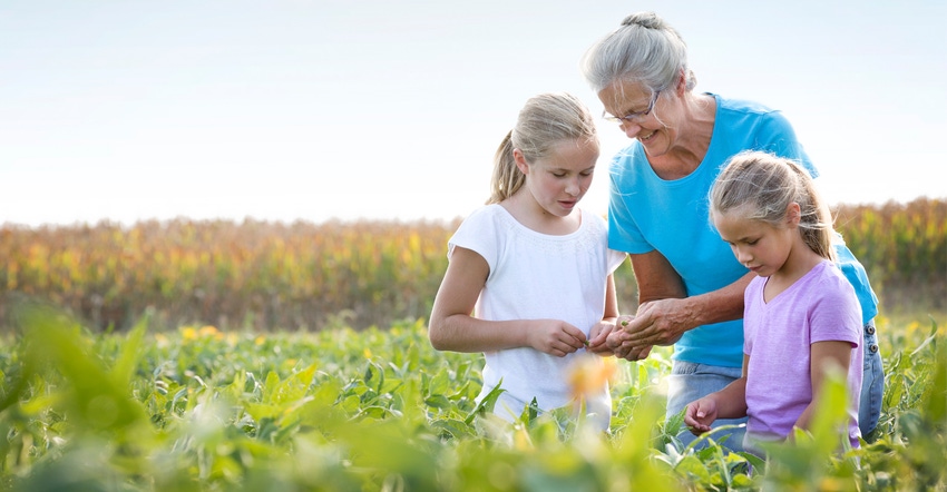 older woman and young children in field looking at crop
