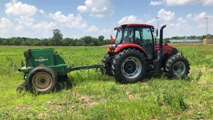 a tractor pulling a drill, seeding a pollinator plot
