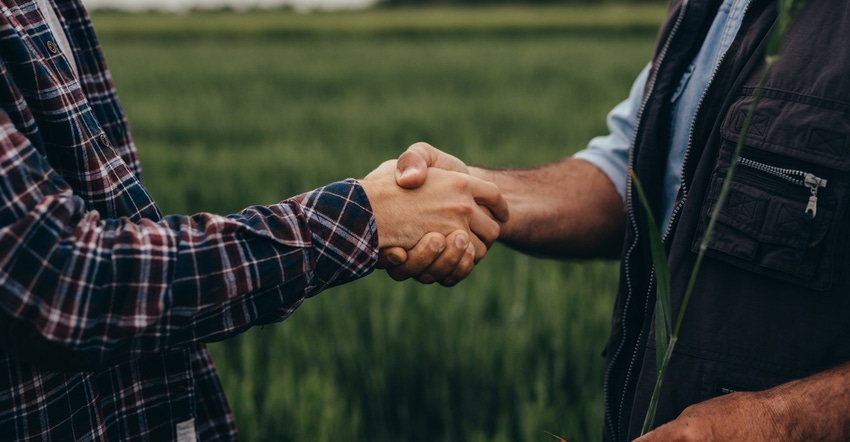 Farmers shaking hands in field