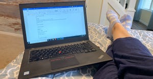 personal point of view while laying on bed looking at laptop and feet