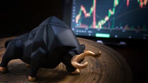 Bull figurine next to laptop with market charts on screen