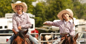 Kelsey Stark (left) and Finley Lynch joke as they ride their horses around the makeup arena
