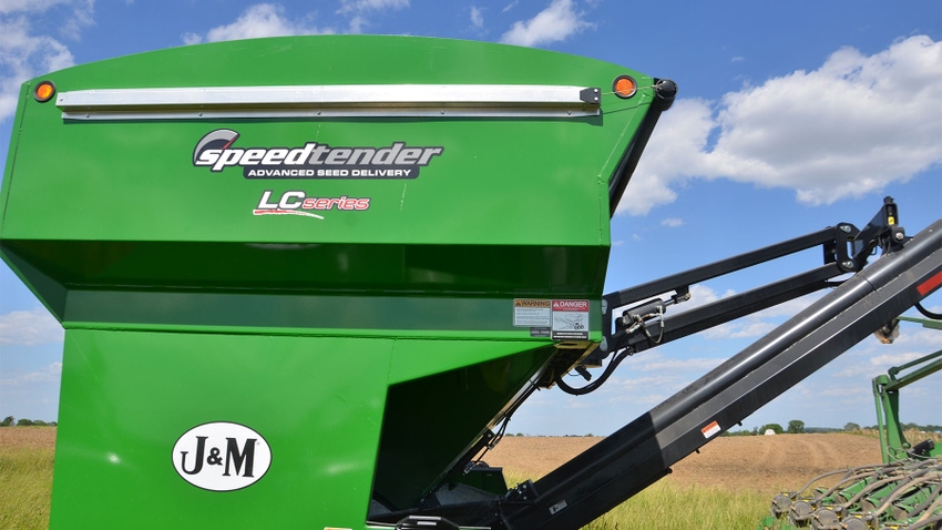a green seed tender sits in a field