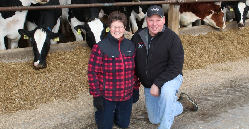 Pam Selz-Pralle and Scott Pralle with Holstein cows behind them