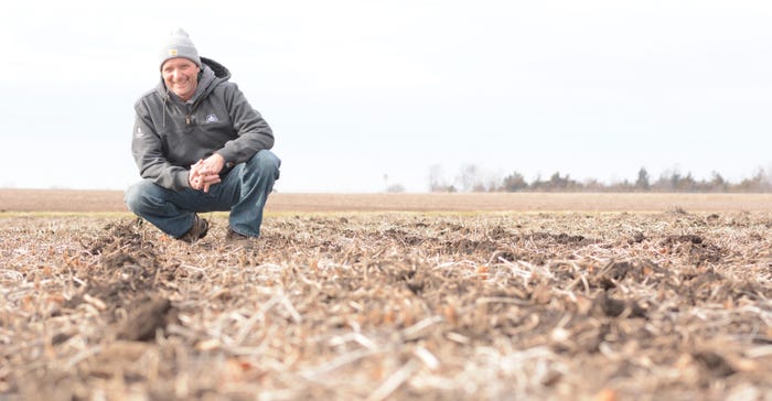 farmer Allyn Buhrow kneeling in a field