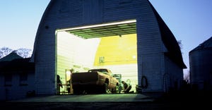 A night photo of a farm shop with a pickup truck, illuminated by the shop lights