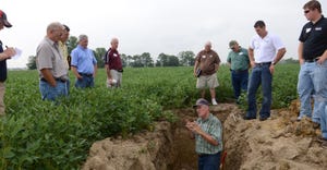 Barry Fisher, a soil conservation expert, shows participants at a field day how cover crop roots create channels for commodit