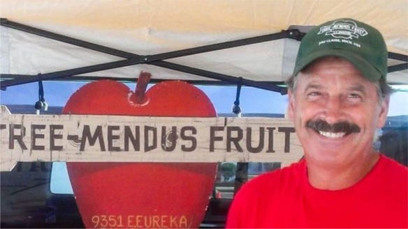 head shot of Bill Teichman, 57, is a third-generation owner of Tree-Mendus Fruit Farm  standing inront of Tree-Mendus Fruit sign