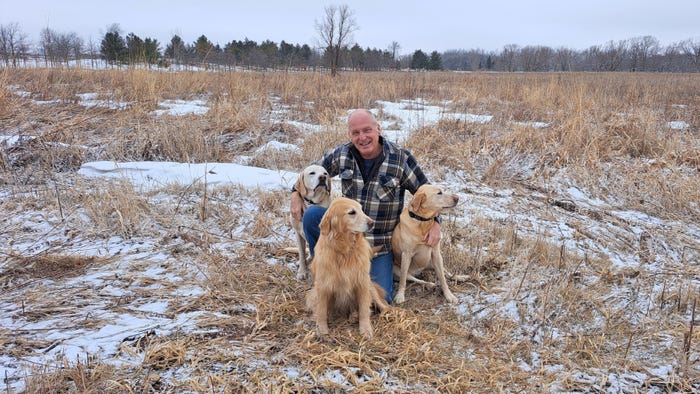 Al Martens of Waupun, Wis., in snowy field with his three dogs