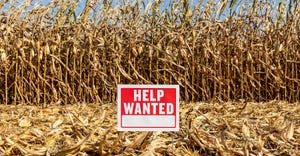 Help wanted sign in partially harvested corn field