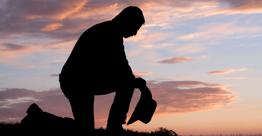 Cowboy praying at sunset