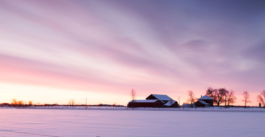 Silhouette of a farm under a sunset with snow