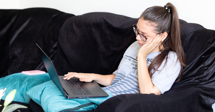Young woman working with her laptop from her couch
