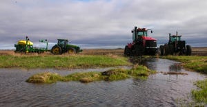 Tractors and planters sitting at the edge of a flooded field 