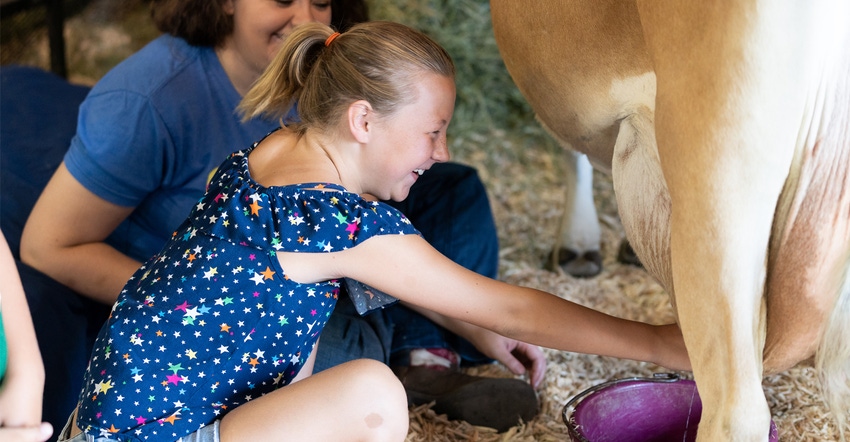 girl tries “I Milked A Cow” display at Iowa state fair