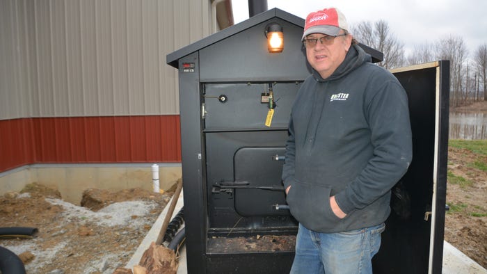 Steve Pitts standing next to a Heatmor wood-fired furnace outside