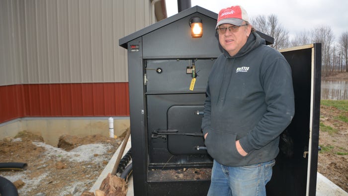 Steve Pitts standing next to a Heatmor wood-fired furnace outside Steve Pitts standing next to a Heatmor wood-fired furnace outside