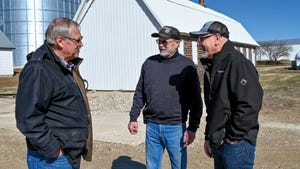 Three men talking with barn in background