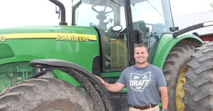 Ron Burns smiling and standing in front of a John Deere tractor