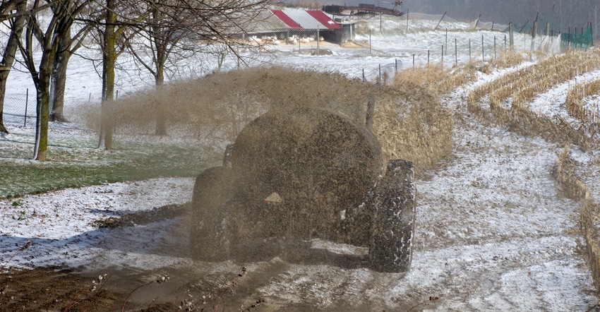 Rear view of a farmer with a large tractor spreading liquid manure on a winter day