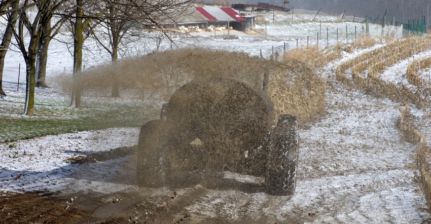 Rear view of a farmer with a large tractor spreading liquid manure on a winter day Rear view of a farmer with a large tractor spreading liquid manure on a winter day