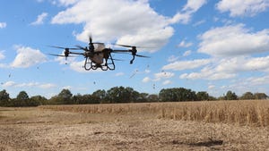 A drone flying over a field dispersing cover crop seeds