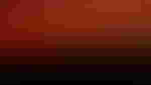 A red sunrise above a cornfield silhouette