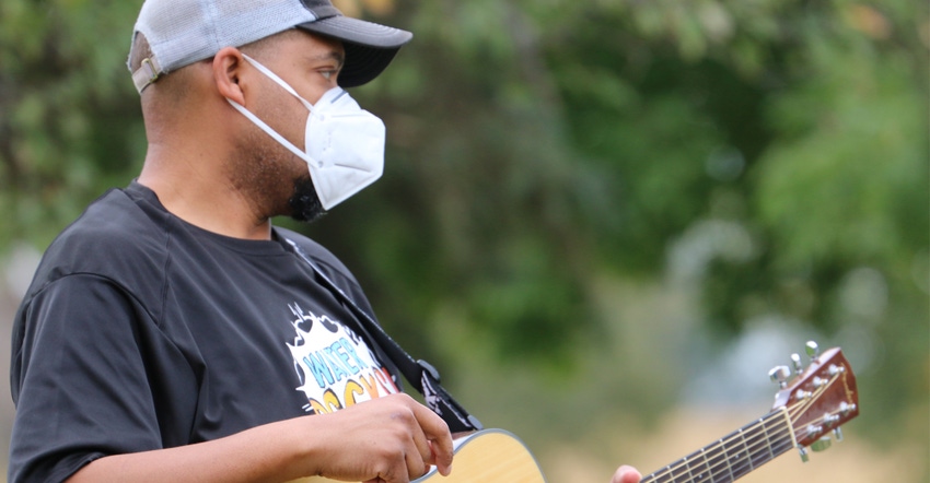 Member of Water Rocks playing guitar wearing mask