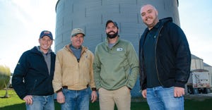 Four men standing in front of grain bin and looking at the camera