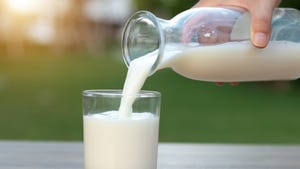 milk being poured into a glass from a carafe