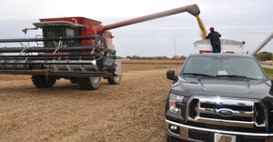 combine unloading soybeans into wagon in field