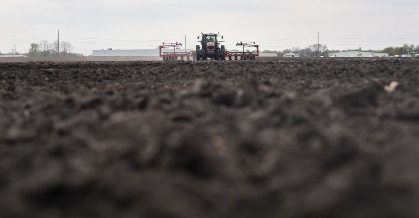 view of tractor and planter in field from perspective on level with the plowed ground view of tractor and planter in field from perspective on level with the plowed ground