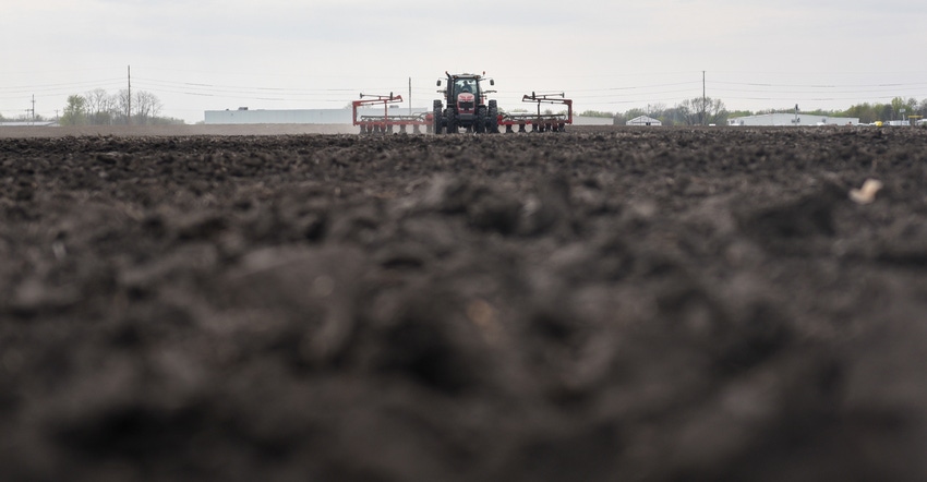 view of tractor and planter in field from perspective on level with the plowed ground